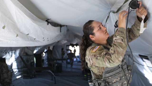 Sgt. Denise Hernandez, a 247th Medical Detachment Soldier and a licensed practical nurse, installs lighting during Operation Guardian Readiness, the 131st Field Hospital's latest field exercise, at Fort Bliss, Texas, June 5, 2021. During Guardian Readiness, 131st FH Soldiers are building proficiency in their ability to stand up their hospital in an austere environment.