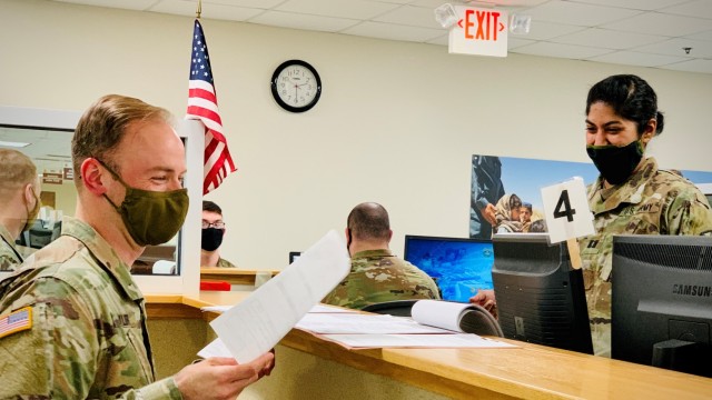 Redeployer Capt. Matthew Taylor receives a readiness-related document from Capt. Delphia Naut, a V Corps battalion surgeon.
