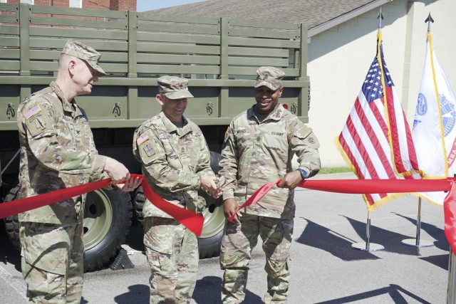 From Left, Col. Joseph R. Kurz, chief of staff, 1st Theater Sustainment Command, Sgt. 1st Class Casey Steiner, maintenance management noncommissioned officer, 1st TSC, and Command Sgt. Maj. Sherman Waters, senior enlisted advisor, Special Troops Battalion, 1st TSC, cut a ribbon during a ceremony dedicating a new static display  at their Fowler Hall headquarters building at Fort Knox, Kentucky, June 14, 2021. During the ceremony a historic M35A2 2 1/2 ton truck was dedicated to Sgt. William S. Seay, and Sp4c Larry G. Dahl, two 1st TSC Soldiers who posthumously earned the Medal of Honor during the Vietnam War. (U.S. Army photo by Sgt. Owen Thez)