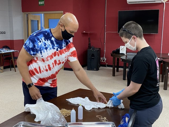 Maj. Anthony Sims-Hall, 1st Theater Sustainment Command, theater mortuary affairs officer, instructs a Soldier on tie-dying techniques at an event held at the MWR building on Camp Arifjan, Kuwait.  Maj. Sims-Hall takes personal passion and hobbies and turns them into resiliency opportunities for Soldiers while deployed. (U.S. Army photo by Capt. Sherelle Hulbert)