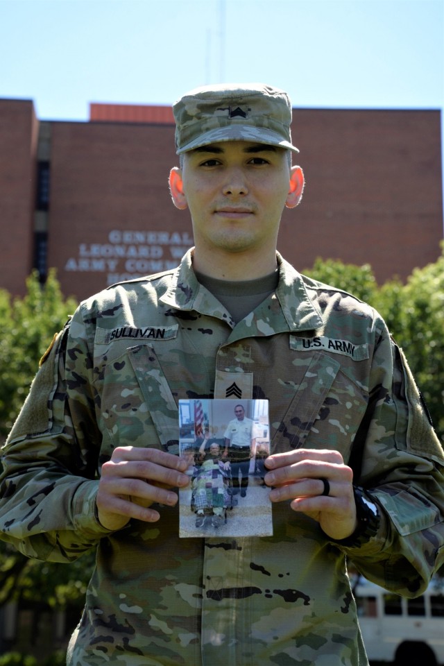 Sgt. David Sullivan, an Optical Laboratory Specialist at the General Leonard Wood Army Community Hospital, stands with a photo of him and his grandfather—a WWII veteran and Army retiree who had adopted his father while traveling in Turkey.