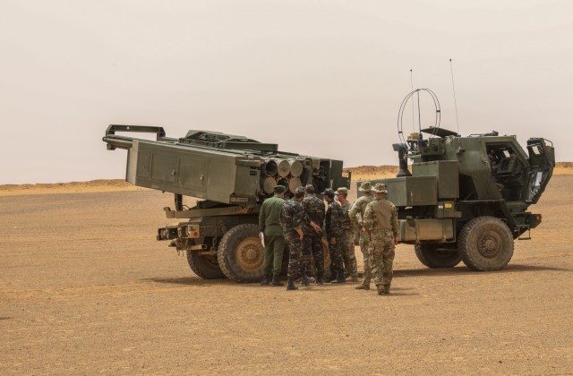 U.S. Army Soldiers assigned to Alpha Battery, 1st Battalion, 77th Field Artillery Regiment, 41st Field Artillery Brigade, speak with Moroccan Ground Troops about the High Mobility Artillery Rocket System during African Lion 2021, at Guirer Libouihi Air Base, on June 8, 2021. The 41st FAB is conducting a suppression of enemy air defense in support of an Airborne joint Forcible Entry during African Lion 2021. This dynamic force employment exercise is their fourth exercise in the Fires Shock series, and a sub-exercise of U.S. Army Europe and Africa’s Defender 21. African Lion 2021 is U.S. Africa Command’s largest, premier, joint, annual exercise hosted by Morocco, Tunisia, and Senegal, 7-18 June. More than 7,000 participants from nine nations and NATO train together with a focus on enhancing readiness for U.S. and partner nation forces. AL21 is a multi-domain, multi-component, and multinational exercise, which employs a full array of mission capabilities with the goal to strengthen interoperability among participants. (U.S. Army photo by Spc. Zack Stahlberg)