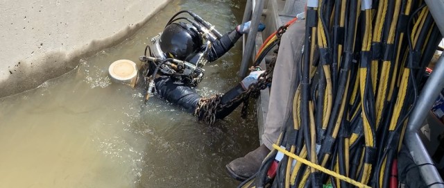 A contract diver enters the water at Pine Creek Lake Dam in Southeastern Oklahoma. Releases were halted so contractors could send a diver 30 feet below the surface in front of the dam to rig crane lifting shackles to move the bulkhead from the...