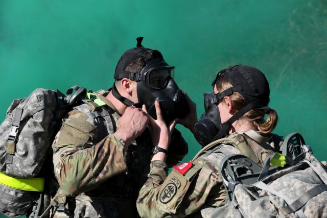 Capt. Laura Benz, right, helps Spc. Colin Hoffmann with his protective mask during a simulated gas attack, Regional Health Command-Pacific Best Leader Competition, Joint Base Lewis-McChord, Wash., June 17, 2021. Both are assigned to U.S. Army...