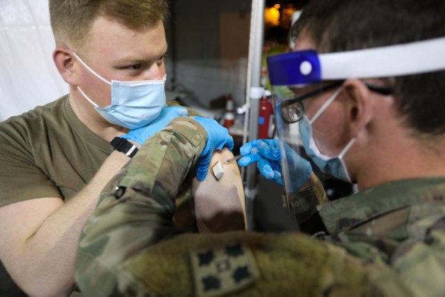 Spc. Ty Hite, a combat medic specialist with 4th Brigade Support Battalion, 1st Striker Brigade Combat Team, receives a COVID-19 vaccination by Spc. Joshua Greene, a fellow combat medic specialist in the same battalion, at the mass vaccination...