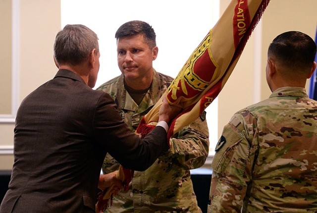 Incoming Garrison Commander Col. John Misenheimer Jr. accepts the colors from ceremony host Vincent Grewatz, Installation Management Command - Training director, during Misenheimer's change of command ceremony with outgoing Garrison Commander Col....