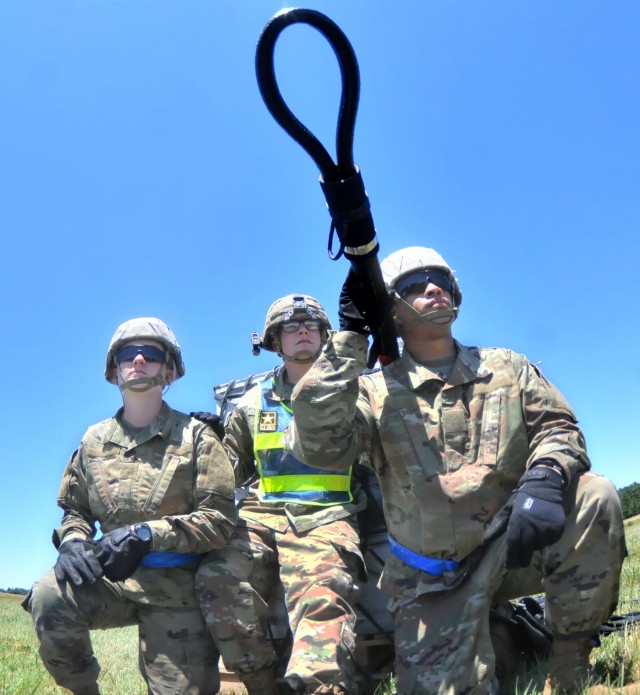 Pfc. Nicki Whiticomb, Staff Sgt. George Avery (an instructor) and Pvt. Dewonn Horne await a UH-60 Black Hawk helicopter just moments prior to a sling load operation June 17 at McLaney Drop Zone. The training event is part of the 89B Ammunition Specialist Course taught by the Ordnance School. (photo by T. Anthony Bell)