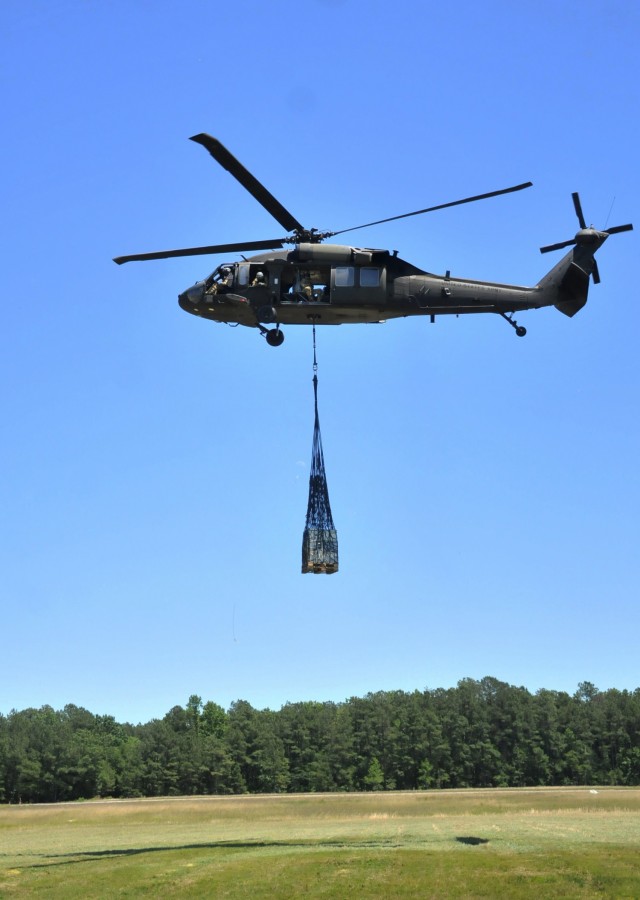 A UH-60 Black Hawk helicopter flies away after picking up cargo from an area of McLaney Drop Zone June 17. Students from the Ordnance School’s 89B Ammunition Specialist Course took turns connecting cargo loads to the aircraft during sling load operations training (photo by T. Anthony Bell).