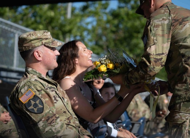 Mrs. Christy Hodermarsky, middle, the spouse of Lt. Col. Daniel G. Hodermarsky, left, the incoming commander of the 3rd Battalion, 67th armored Regiment, 2nd Armored Brigade Combat Team, 3rd Infantry Division, receives a bouquet of yellow roses as the a symbolic welcome gesture from the unit during a change of command ceremony on Cottrell Field at Fort Stewart, Georgia, June 16, 2021. (U.S Army Photo by Spc. Devron Bost)