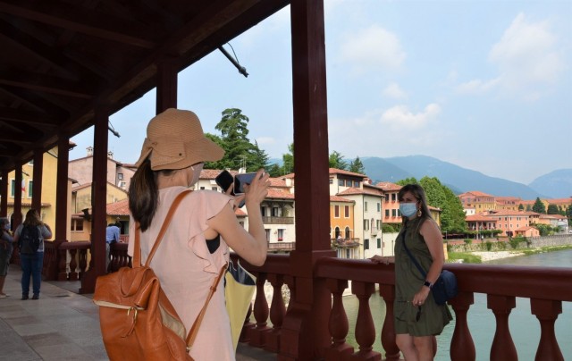 VICENZA, Italy - Arisa Ueshiro, one of the “Benvenuti” tour participants takes a moment for a picture of classmate Dali Prado, while crossing  the Ponte Vecchio, the renowned wooden bridge in Bassano del Grappa during their day trip June 18, 2021. The Benvenuti program resumed to welcome new arrivals and the first destination was Bassano sights and a stop in Nove.
