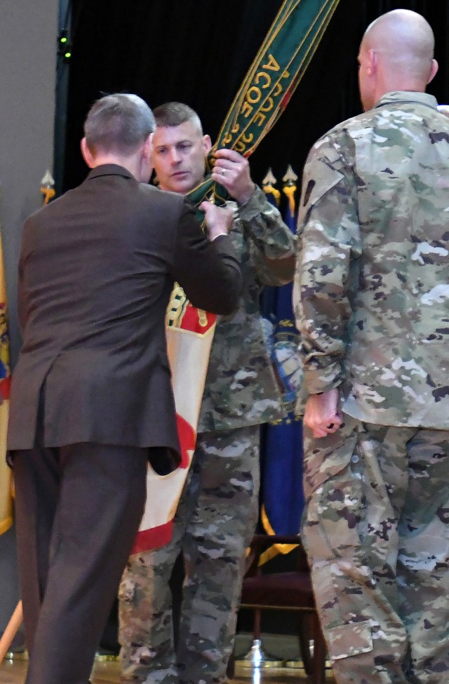 Incoming Garrison Commander Col. CJ King takes the Fort Knox Garrison guidon from Vincent Grewatz, director of U.S. Army Installation Command Directorate - Training, during a July 26, 2019 change of command ceremony at Waybur Theater.
