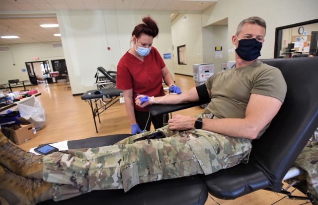 Fort Knox Garrison Commander Col. CJ King looks away as a blood draw needle is inserted. He and Command Sgt. Maj. William Fogle participated in the second of two American Red Cross blood draw events July 29, 2020, to offer support and...