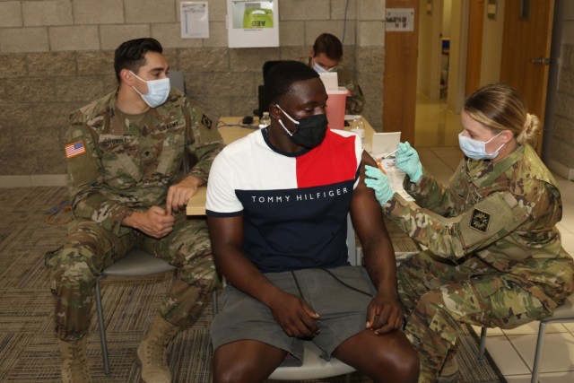 First Lt. Katelyn Harding (right), a physician assistant with 1st Battalion, 144th Field Artillery Regiment of the California Army National Guard, administers a COVID-19 vaccine to a member of the Fort Irwin community June 24 at the Dr. Mary E. Walker Center on Fort Irwin, Calif., as Spc. Jacob Gutierrez (far left), a health care specialist with 1st Bn., 144th FA Regt., watches. Harding, a San Diego native, Gutierrez, a Rancho Cucamonga native, and other medical personnel with 1st Bn., 144th FA Regt. augmented the COVID-19 vaccine event hosted by Weed Army Community Hospital. (Photo by Kimberly Hackbarth/ Weed ACH Public Affairs)