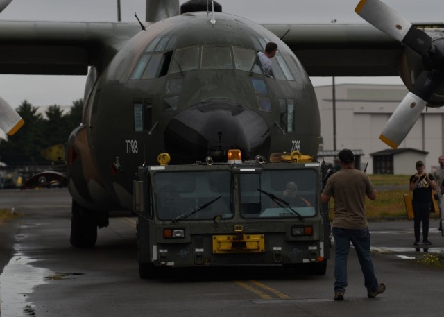 U.S. Air Force Senior Master Sgt. Joshua Pechacek, 62nd Aircraft Maintenance Squadron superintendent, guides a towing vehicle driver while he tows a C-130E Hercules at Joint Base Lewis-McChord, Washington, June 13, 2021. The 62nd AMXS worked...