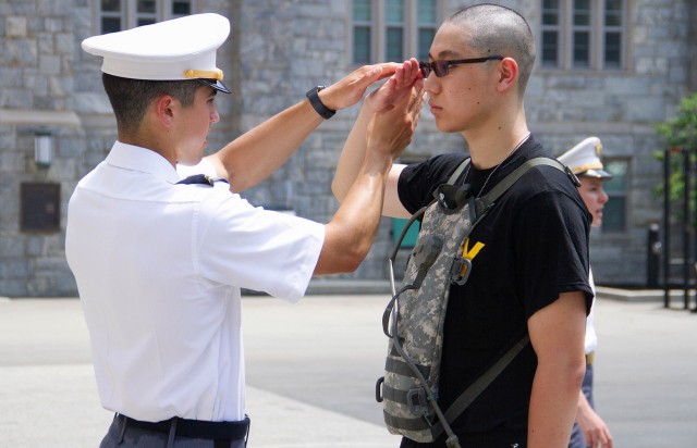 A U.S. Military Academy at West Point junior teaches a new cadet how to salute during Reception Day Monday.