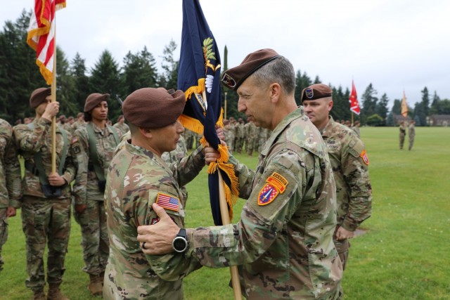 Maj. Gen. Scott Jackson, Commanding General, Security Force Assistance Command, hands the unit colors to Col. Jonathan Chung during the 5th Security Force Assistance Brigade Assumption of Command Ceremony, June 30, 2021 at Joint Base Lewis McChord, Washington.