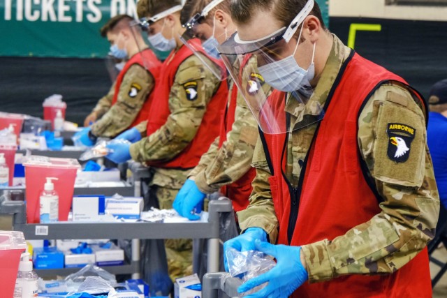 U.S. Army Spc. Brandon Hatfield, right, a native of Birmingham, Alabama, and a healthcare specialist from 2nd Brigade Combat Team, 101st Airborne Division (Air Assault), prepares his work station before administering vaccines to local community...