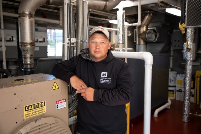 Engineer Tony Frost kneels as he works on a generator aboard the Quad Cities heavy lift crane barge.