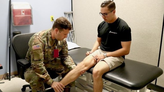 1st Lt. Nicholas Wankum, left, an Army physical therapist at Madigan Army Medical Center, evaluated the progress made by Marine Staff Sgt. Dalton Everhart in his range of motion since Everhart came to the emergency department after an injury nearly a month before this September 2019 visit.