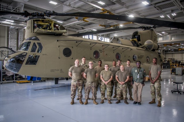 The team responsible for the complete overhaul of a CH-47 Chinook helicopter that was battle damaged from a hard landing while serving in Iraq pose for a group photo in front of the helicopter at the Connecticut National Guard's 1109th Theater...