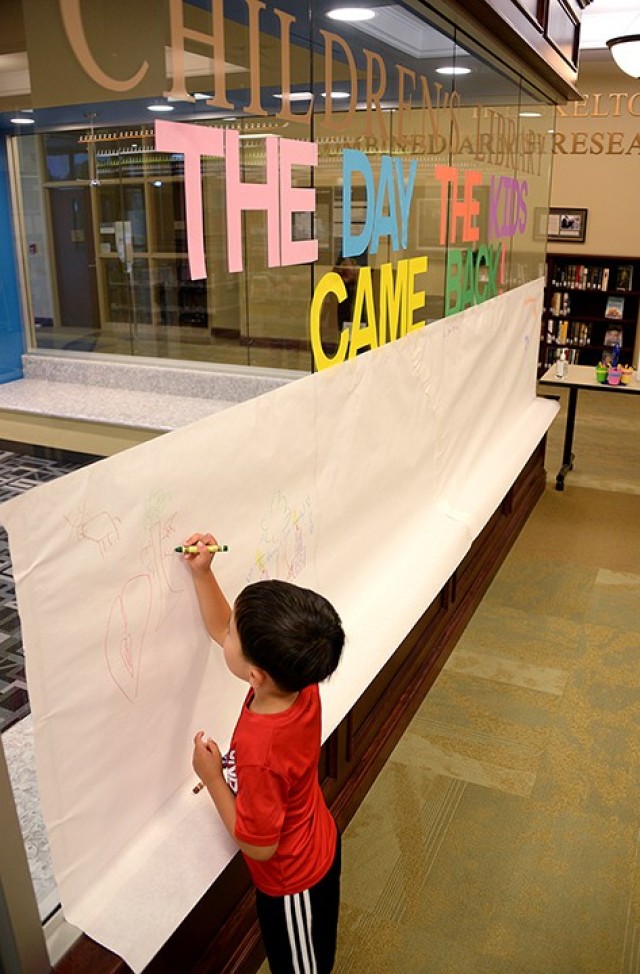 To help celebrate the reopening of the library, 6-year-old Colton Lem draws hearts, a deer and a tree on a paper "canvas" outside the children's room of the Combined Arms Research Library July 6. Photo by Prudence Siebert/Fort Leavenworth Lamp