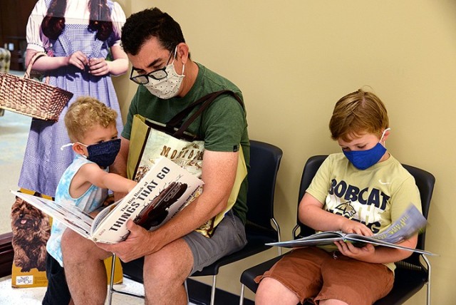 Chris Norman and his children, 3-year-old Rex and 6-year-old Ruby, look through some of their book selections July 6 in the children's room of the Combined Arms Research Library. The family had participated in the StoryWalks positioned outside the...
