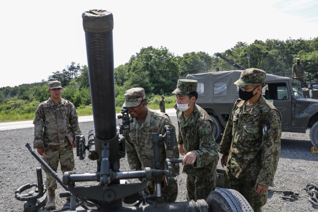 U.S. Army Soldiers assigned to 1st Battalion, 28th Infantry Regiment, 3rd Infantry Division, look through the optics of a Japan Ground Self-Defense Force 120mm mortar as JGSDF members observe during an equipment display on Aibano Training Area, Japan, June 28, 2021, as part of exercise Orient Shield. Orient Shield is the largest U.S. Army and JGSDF bilateral field training exercise being executed in various locations throughout Japan to enhance interoperability and test and refine multi-domain and cross-domain operations.