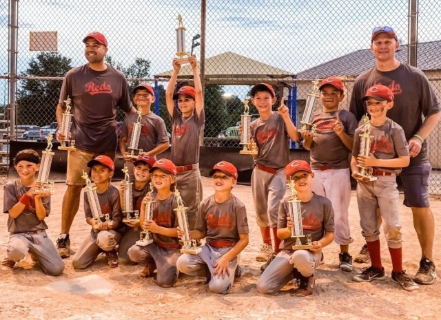 The 2021 Fort Knox Reds celebrate their undefeated season following a double header win.