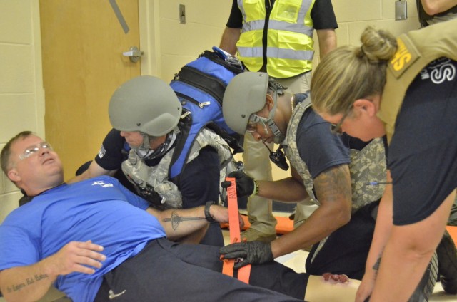 Donny Plaster, assistant chief of training, Fort Campbell Fire and Emergency Services, left, works with Wes LaFortune, district chief, Fort Campbell Fire and Emergency Services, center, and Sgt. Thomasa Munroe, Montgomery County Sheriff’s Office, to prepare a shooting victim for medical evacuation during Active Attack Integrated Response training, hosted July 12-16 at Jackson Elementary School.