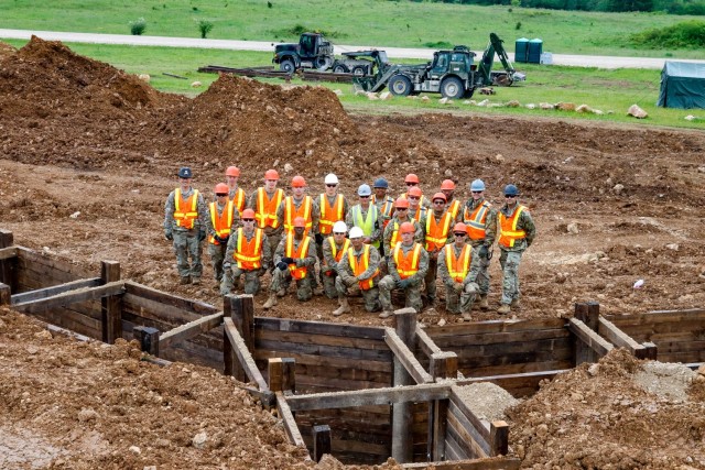 Members of the Joint Multinational Readiness Center’s Troop Construction Program and 2nd Cavalry Regiment's Third Platoon, Argonaut Troop, Regimental Engineer Squadron, stand alongside a 100-meter platoon-minus trench June 4 that they had been...