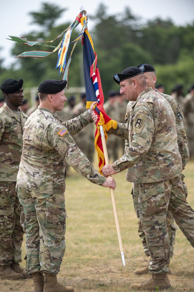 Maj. Gen. Richard Johnson, commanding general of Division West, 1st Army at Fort Hood, Texas, passes the 181st Multi-Functional Training Brigade flag to Col. Ronald “R.J.” Hughes on June 24, 2021, during a change of command ceremony for the...