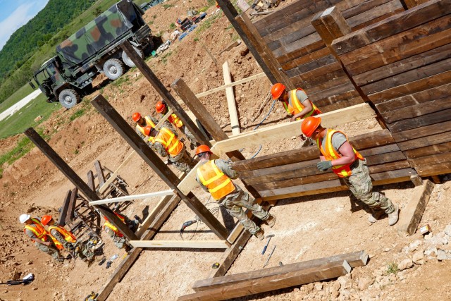 Engineers with the 2nd Cavalry Regiment's Regimental Engineer Squadron and the Joint Multinational Readiness Center’s Troop Construction Program work on a 100-meter trench on Hohenfels Training Area, Hohenfels, Germany, June 3, 2021. The trench...