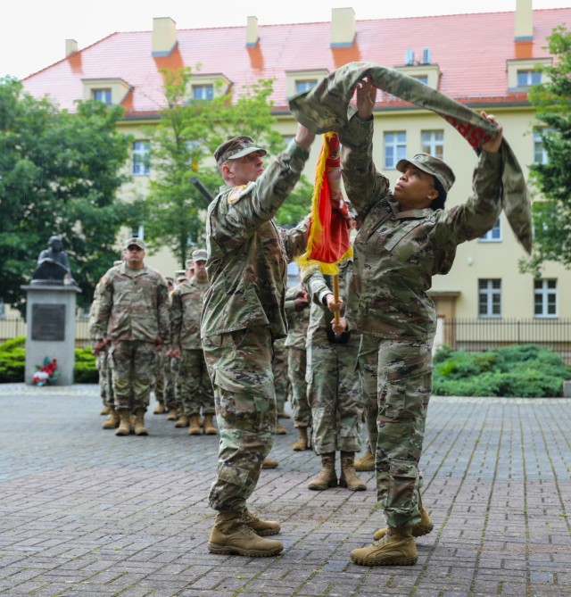 The 49th Transportation Battalion Commander Lt. Col. Andrew Carpenter and Command Sgt. Maj. Tamara Williams uncase their colors during a transfer of authority ceremony in Żagań, Poland, July 14, 2021. Uncasing the colors signifies that the...