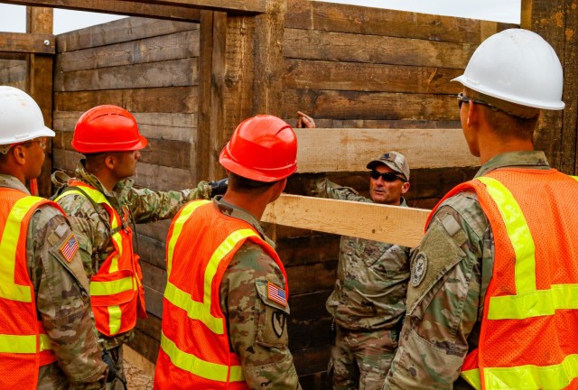 Chief Warrant Officer 2 Raymond Cowden, a construction engineering technician with the Joint Multinational Readiness Center’s Troop Construction Program, talks with engineer Soldiers from third platoon, Argonaut Company, Regimental Engineer...