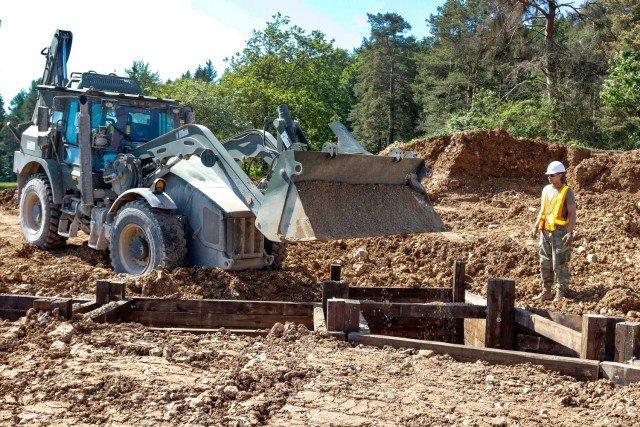 Spc. Matthew Lynch, a horizontal construction engineer with third platoon, Argonaut Troop, Regimental Engineer Squadron, 2nd Cavalry Regiment, right, provides a safety guide as Pvt. Cole Augustine, also a horizontal construction engineer with...