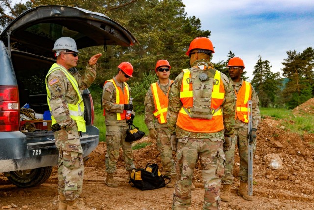 Chief Warrant Officer 2 Raymond Cowden, a construction engineering technician with the Joint Multinational Readiness Center’s Troop Construction Program, talks with engineer Soldiers from third platoon, Argonaut Company, Regimental Engineer...