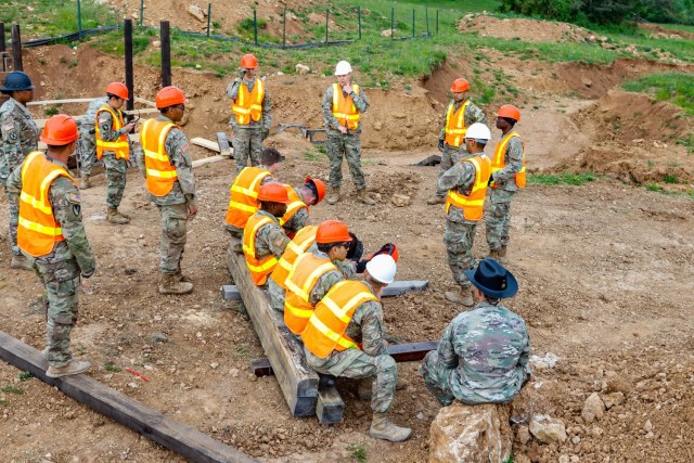 Engineers with the 2nd Cavalry Regiment's Regimental Engineer Squadron and the Joint Multinational Readiness Center’s Troop Construction Program conduct a morning meeting before beginning work on a 100-meter trench on Hohenfels Training Area,...