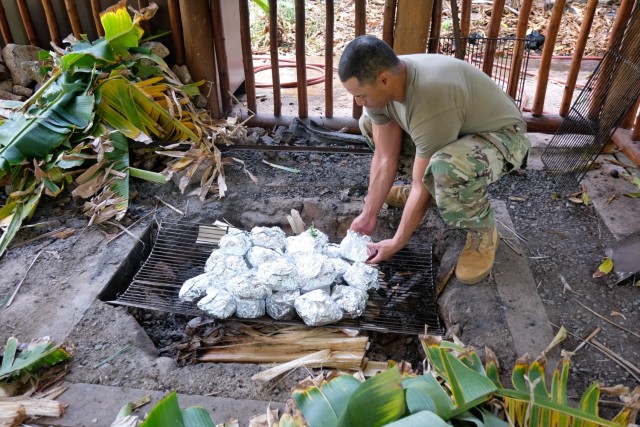U.S. Army Sgt. Boyd Lauano, of the 9th Mission Support Command’s Task Force Oceania, places Lu Pulu, a Tongan dish inside an Umu, to cook at the Polynesian Cultural Center June 6. The Umu, an underground oven used to trap heat to cook food, is used by many communities to cook various dishes such as Hawaiian imu, the Mexican barbacoa, and the New England clam bake. (U.S. Army photo by Sgt. Teresa Cantero)