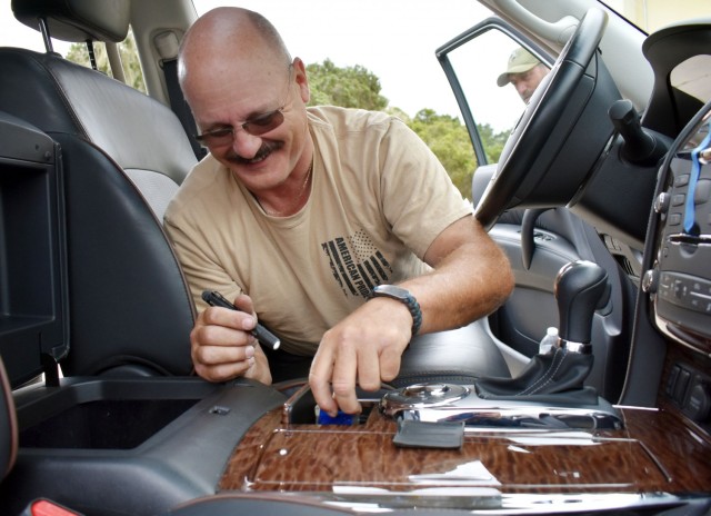 Officer Michael Mancini, a police officer with the Presidio of Monterey Police Department, smiles as he finds hidden contraband during vehicle interdiction training at the Stilwell Community Center, Ord Military Community, July 13.