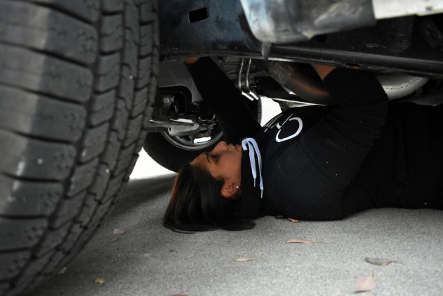 Officer Monica Garcia-Gonzalez, a Presidio of Monterey security guard, searches under a vehicle for hidden contraband during vehicle interdiction training at the Stilwell Community Center, Ord Military Community, July 13.