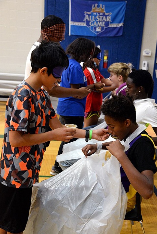 Thirteen-year-old Hudson Miller feeds babyfood to his teammate 12-year-old Zarden Denson while racing to accurately feed and consume the most the quickest during Teen Summer Adventure Camp participants July 12 at Harrold Youth Center. Photo by...
