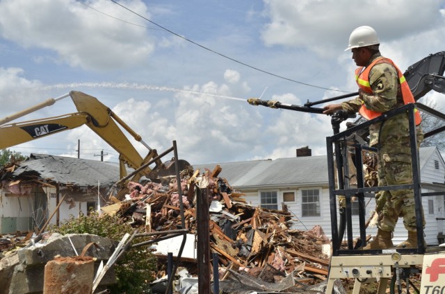 First Lieutenant Robert Dietrich III, 326th Brigade Engineer Battalion, 1st Brigade Combat Team, 101st Airborne Division (Air Assault), uses a hydraulic seeder to prevent dust buildup, July 19, as Fort Campbell Directorate of Public Works Roads and Grounds employees work to demolish the vacated Building 873.