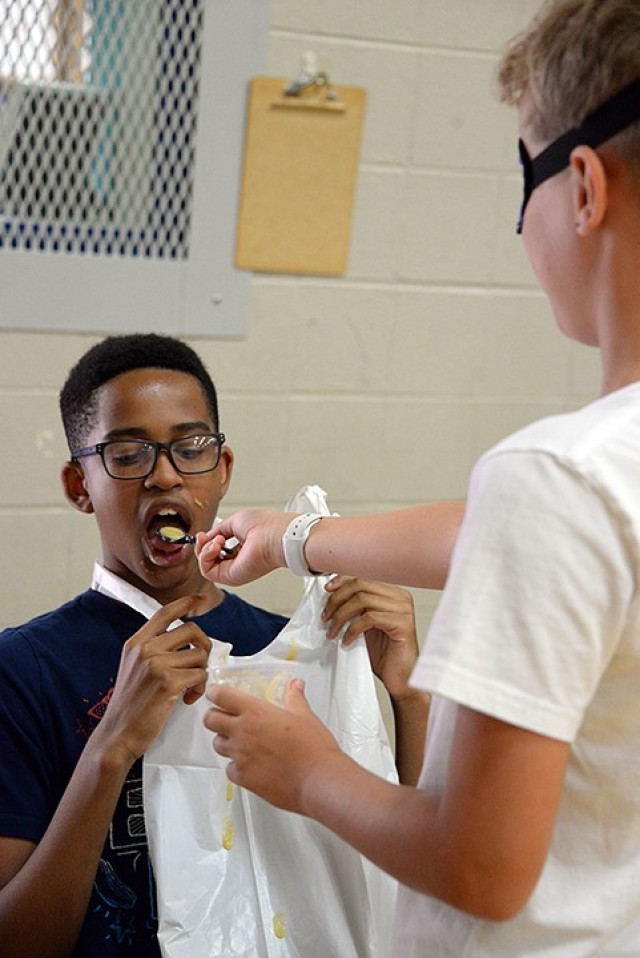 Thirteen-year-old Micah Austin tries to consume most of the babyfood being fed to him by blindfolded 12-year-old Aidan Nuce during a race with other participants July 12 during Teen Summer Adventure Camp at Harrold Youth Center. Photo by Prudence...
