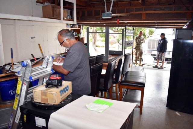 Movers pack the household goods of the Whetstone family as Col. Varman Chhoeung, commander of U.S. Army Garrison Presidio of Monterey, speaks with Zane Whetstone, who is moving to Japan with his family, in Pebble Beach, Calif., July 16. Chhoeung accompanied a quality assurance inspector with the Presidio of Monterey Transportation Office to speak with service members and their families and ensure their permanent-change-of-station moves are going well.
