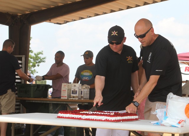The 75th Field Artillery Brigade command team of Command Sgt. Maj. John Black and Col. David Norris make the ceremonial first cuts of the 100th anniversary cake.