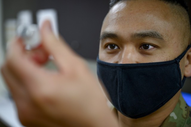 Staff Sgt. Owen Wijaya, 341st Operational Medical Readiness Squadron medical technician, inspects a COVID-19 vaccine June 30, 2021, at Malmstrom Air Force Base, Mont. Administering vaccines supports the readiness and safety of Airmen. (U.S. Air Force photo by Senior Airman Jacob M. Thompson)