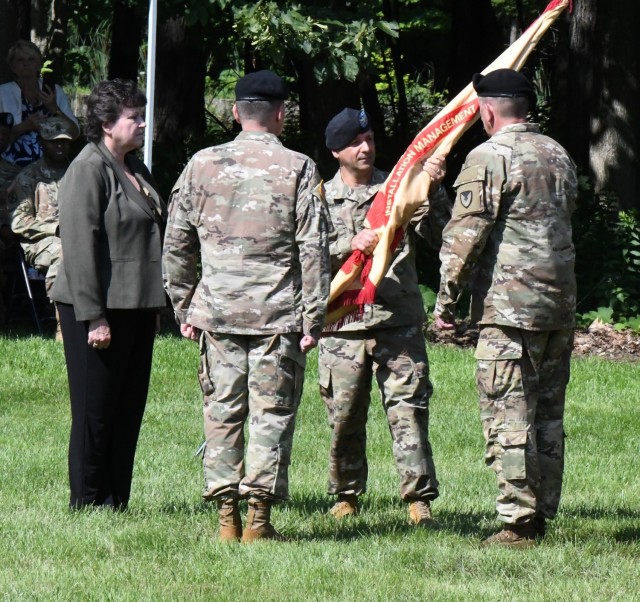 Col. James J. Zacchino Jr. passes the unit colors to Command Sgt. Maj. Roberto Munoz, Fort Drum garrison senior enlisted adviser, during the Fort Drum Garrison change of command ceremony July 23 outside LeRay Mansion. Zacchino assumed command of the garrison from outgoing commander, Col. Jeffery Lucas. (Photo by Mike Strasser, Fort Drum Garrison Public Affairs)