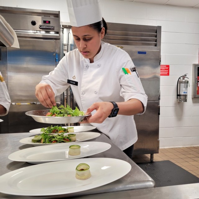 Pfc. Jennifer Payan, a culinary specialist with 1st Squadron, 89th Cavalry Regiment, 2nd Brigade Combat Team, helps plate a salad, as the Student Chef team rehearses their menu in preparation for the 2021 American Culinary Federation (ACF) National Competition in Orlando, Florida, Aug. 2-5. (Photo by Mike Strasser, Fort Drum Garrison Public Affairs)