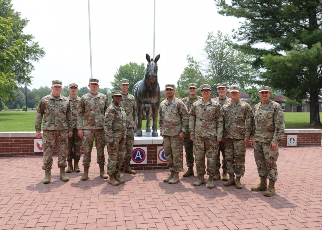 Members of the 1st Theater Sustainment Command&#39;s staff judge advocate office gather outside Fowler Hall at Fort Knox, Kentucky with a statue of the unit&#39;s mascot, Sgt. Blackjack.