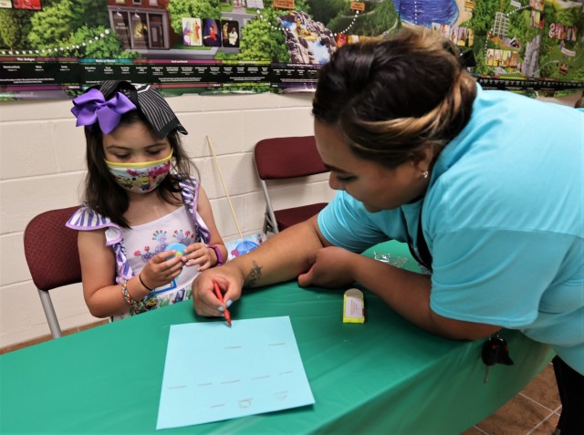 A volunteer helps a young VBS attendee with her decoding activity.